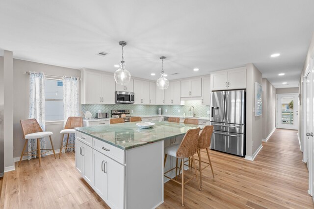 kitchen featuring white cabinetry, visible vents, stainless steel appliances, and a center island