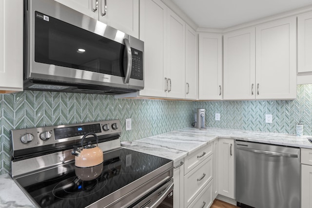 kitchen with light stone countertops, white cabinetry, and stainless steel appliances