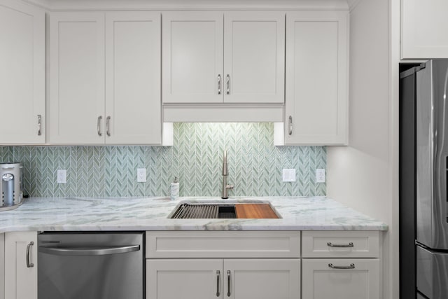 kitchen featuring appliances with stainless steel finishes, a sink, white cabinetry, and light stone countertops