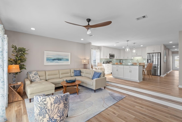 living room featuring light wood-type flooring, visible vents, and recessed lighting