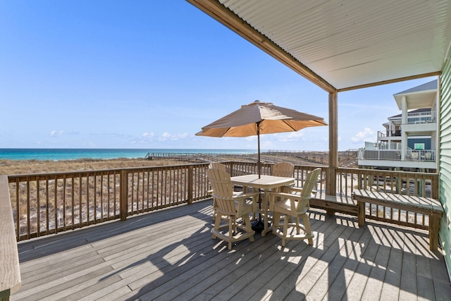 wooden terrace with a beach view, outdoor dining area, and a water view