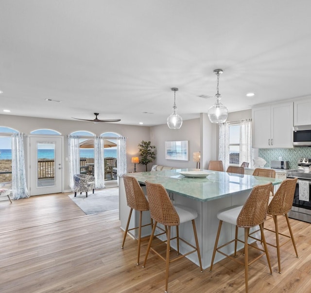 kitchen with stainless steel appliances, a kitchen island, light wood-style flooring, and decorative backsplash