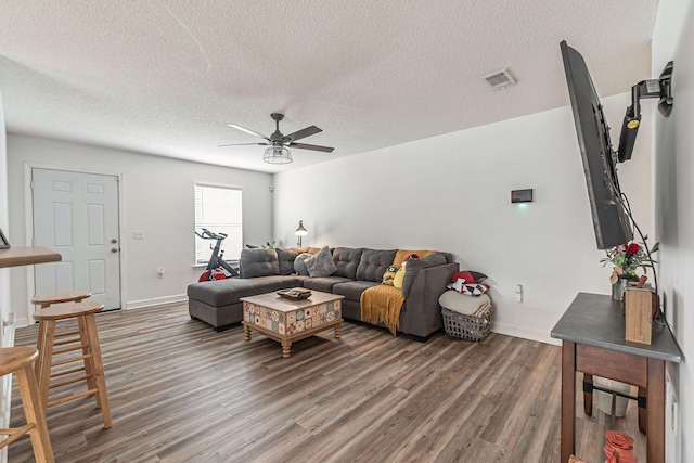 living room with visible vents, a ceiling fan, a textured ceiling, wood finished floors, and baseboards