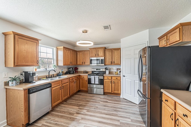 kitchen with appliances with stainless steel finishes, light countertops, visible vents, and a sink