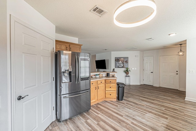 kitchen featuring a textured ceiling, visible vents, light countertops, stainless steel fridge with ice dispenser, and light wood finished floors