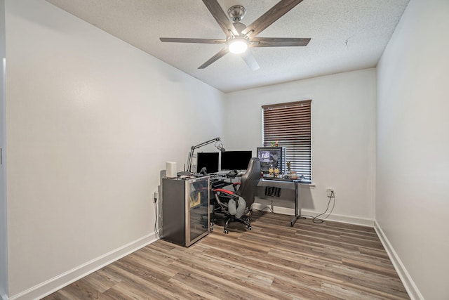 office area with ceiling fan, a textured ceiling, baseboards, and wood finished floors