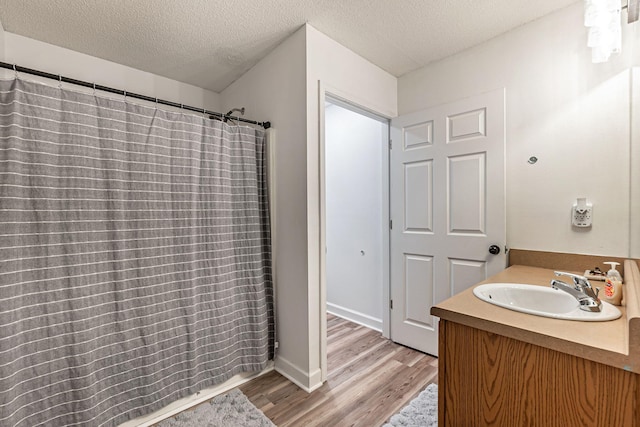 bathroom with a textured ceiling, wood finished floors, vanity, and a shower with curtain