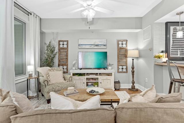 living area featuring baseboards, ceiling fan, visible vents, and wood finished floors