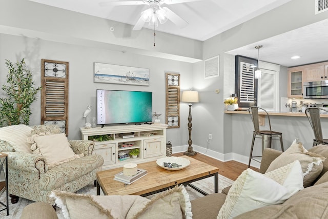 living room featuring visible vents, ceiling fan, baseboards, and wood finished floors