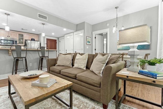 living area with baseboards, light wood-type flooring, visible vents, and recessed lighting