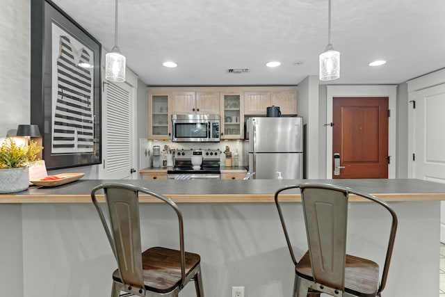 kitchen with dark countertops, glass insert cabinets, stainless steel appliances, and decorative light fixtures