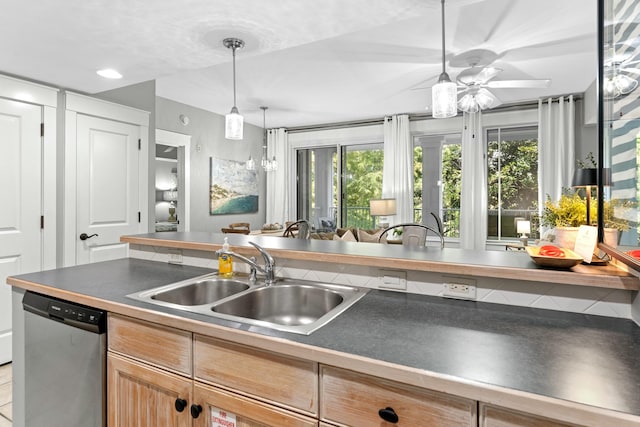 kitchen with dark countertops, decorative light fixtures, a sink, and stainless steel dishwasher