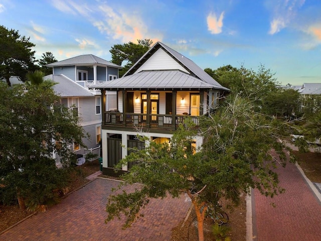 back of house with metal roof, a standing seam roof, and a balcony