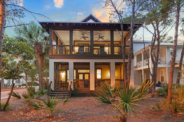 back of house at dusk with a ceiling fan, covered porch, and a balcony