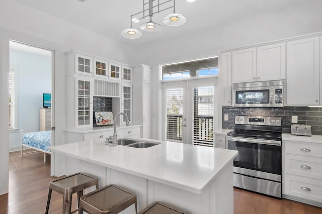 kitchen featuring stainless steel appliances, a sink, white cabinetry, dark wood-style floors, and tasteful backsplash