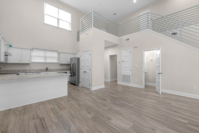 kitchen with light wood finished floors, baseboards, and stainless steel refrigerator with ice dispenser