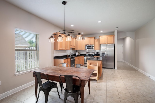 interior space featuring arched walkways, appliances with stainless steel finishes, light brown cabinets, light tile patterned flooring, and baseboards