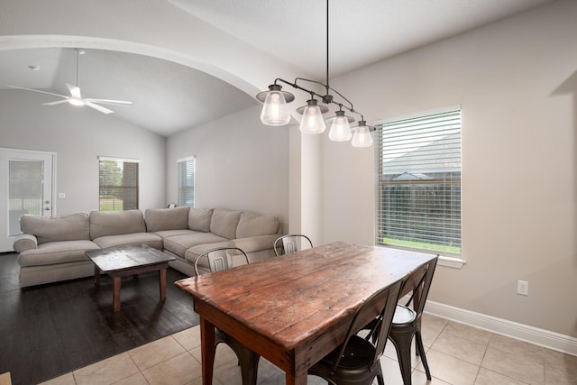 dining area with light tile patterned floors, ceiling fan, arched walkways, baseboards, and vaulted ceiling