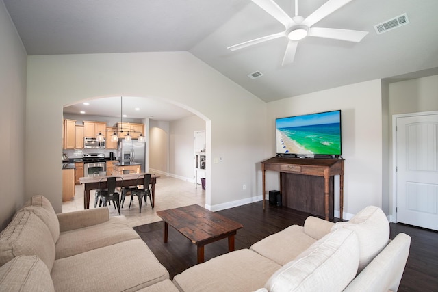 living room featuring arched walkways, visible vents, lofted ceiling, and light wood finished floors