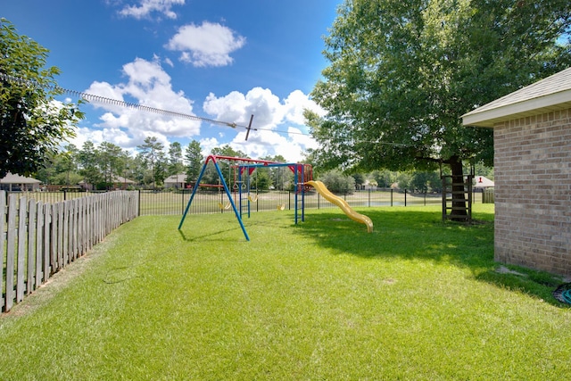 communal playground featuring a fenced backyard and a lawn