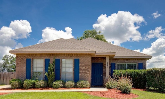 view of front of property with brick siding, a shingled roof, and fence