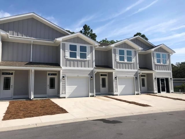 view of front of home with a garage, concrete driveway, a shingled roof, and board and batten siding