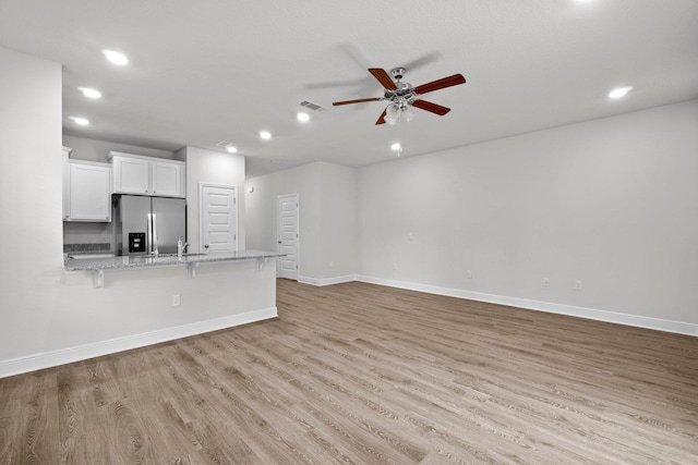 unfurnished living room featuring light wood-type flooring, ceiling fan, baseboards, and recessed lighting