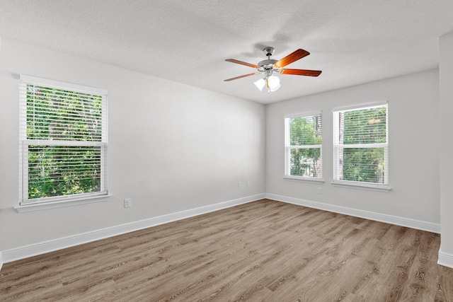 empty room featuring a healthy amount of sunlight, baseboards, and wood finished floors