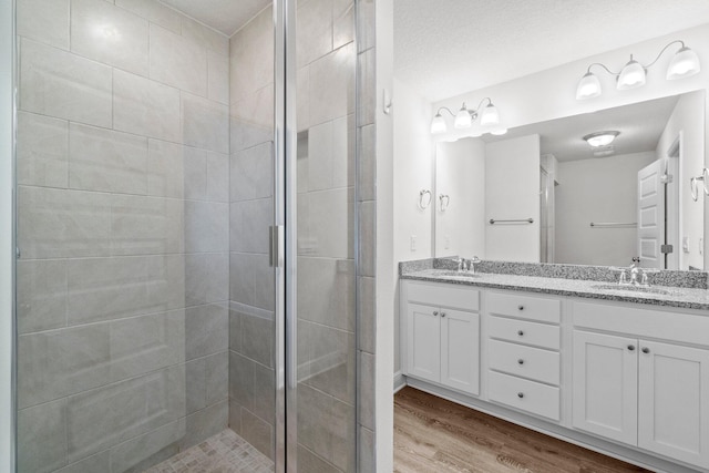 full bathroom with a stall shower, a sink, and wood finished floors