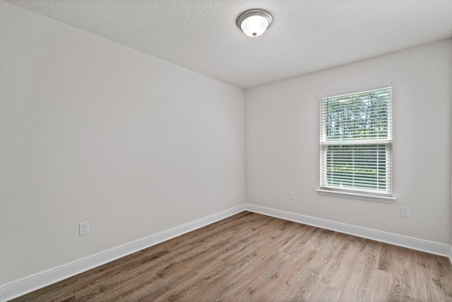 spare room featuring a textured ceiling, baseboards, and wood finished floors