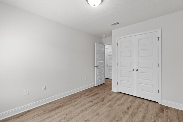 unfurnished bedroom featuring light wood finished floors, a closet, visible vents, and baseboards