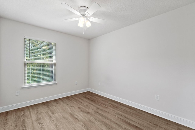 unfurnished room with ceiling fan, a textured ceiling, baseboards, and wood finished floors