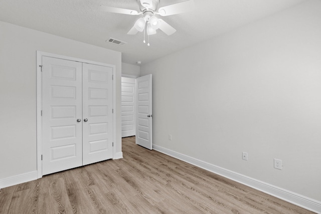 unfurnished bedroom featuring a ceiling fan, visible vents, baseboards, a closet, and light wood-type flooring