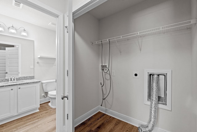 clothes washing area featuring a sink, light wood finished floors, visible vents, and hookup for an electric dryer