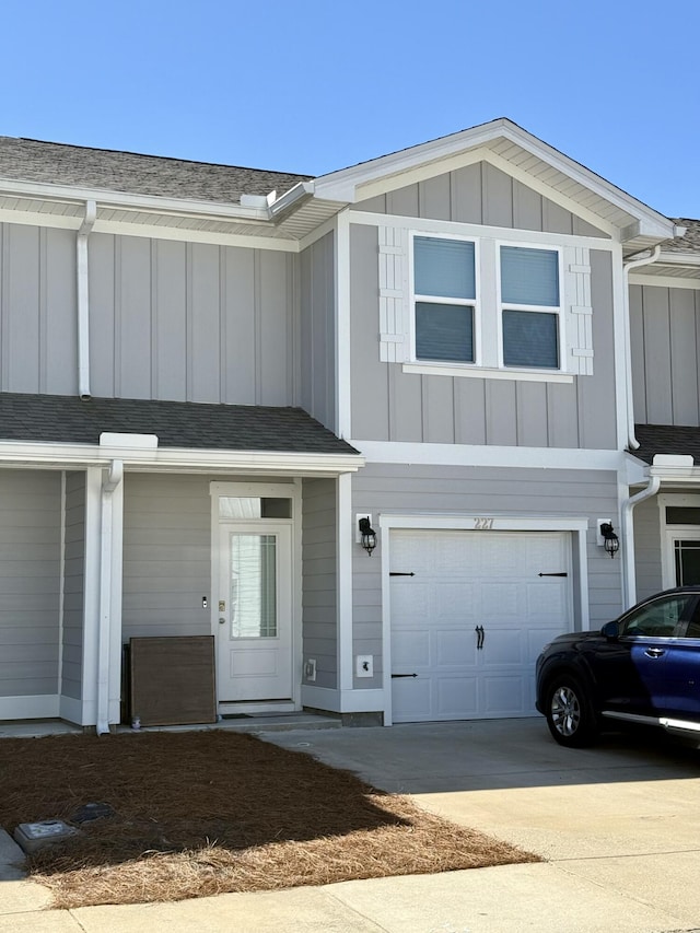 townhome / multi-family property with board and batten siding, roof with shingles, and driveway