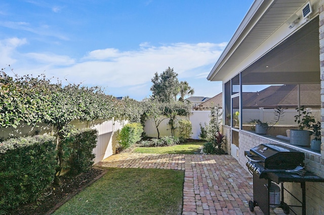 view of yard with a sunroom, a fenced backyard, and a patio