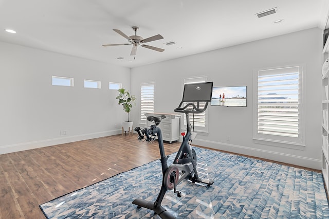 exercise area with visible vents, ceiling fan, baseboards, and wood finished floors