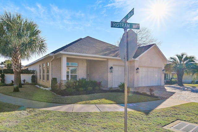 ranch-style home with a garage, brick siding, decorative driveway, and a front yard