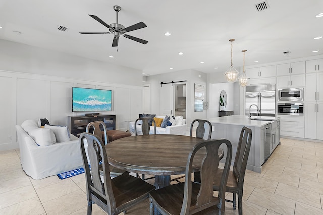 dining area featuring a barn door, visible vents, ceiling fan, a decorative wall, and recessed lighting