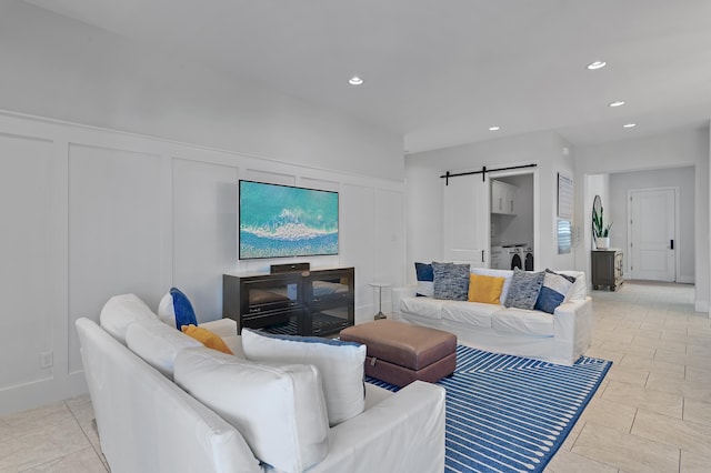 living room with recessed lighting, a decorative wall, washing machine and clothes dryer, and a barn door