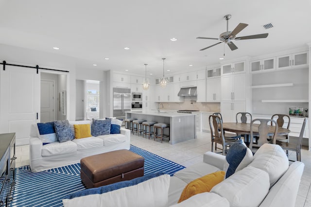 living area with light tile patterned flooring, visible vents, recessed lighting, and a barn door