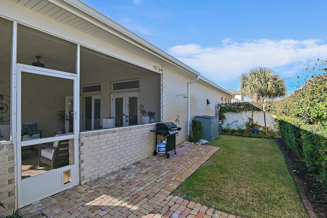 view of side of property featuring brick siding, a yard, a patio, a sunroom, and a fenced backyard