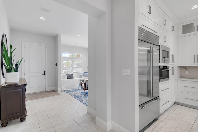 kitchen featuring recessed lighting, glass insert cabinets, white cabinets, and built in appliances