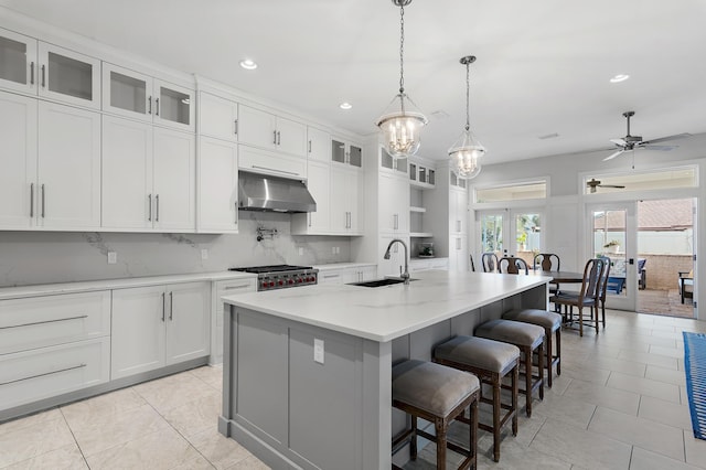 kitchen with french doors, a sink, white cabinets, and under cabinet range hood