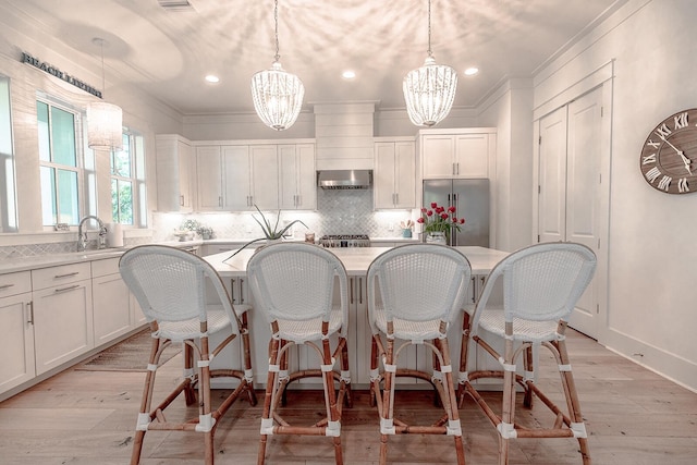 kitchen with a center island, a notable chandelier, high end refrigerator, and exhaust hood