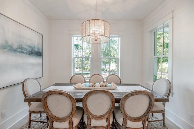 dining room featuring a healthy amount of sunlight, crown molding, a notable chandelier, and baseboards