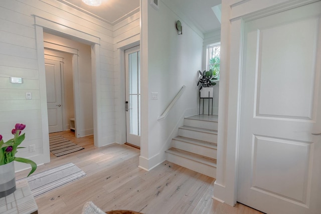 foyer entrance featuring visible vents, ornamental molding, light wood-type flooring, baseboards, and stairs