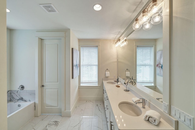 bathroom with marble finish floor, a garden tub, double vanity, visible vents, and a sink