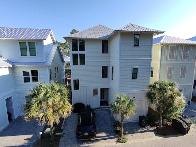 view of front of home with decorative driveway, metal roof, a standing seam roof, and an attached garage