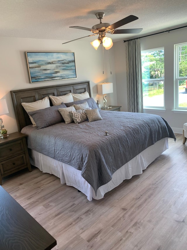 bedroom with a textured ceiling, wood finished floors, and a ceiling fan